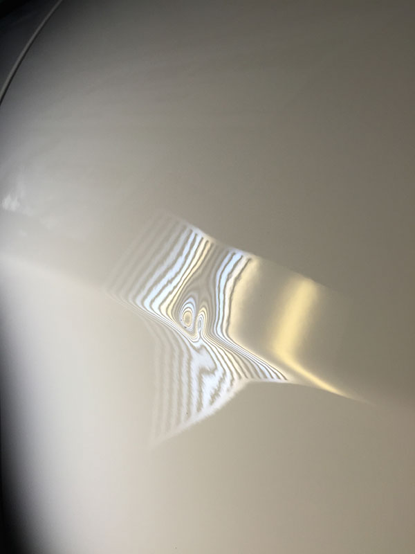 Dent visible on Jeep body panel before paintless dent repair in Fife Lake, Michigan