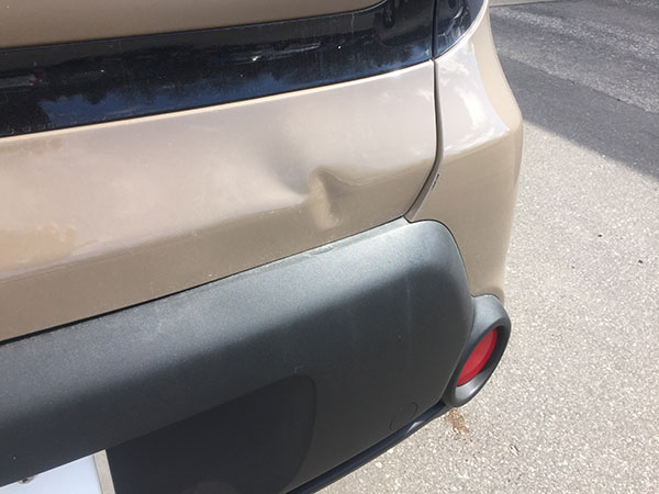 Kia rear panel showing dent damage before paintless dent repair at Collins Dent Werks in Fife Lake, Michigan