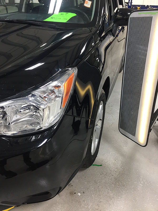 Large dent in Subaru front fender before paintless dent repair at Collins Dent Werks in Fife Lake, Michigan