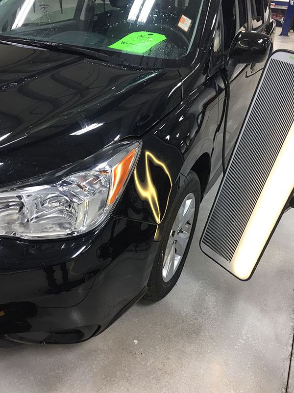 Large dent in Subaru front fender before paintless dent repair at Collins Dent Werks in Fife Lake, Michigan