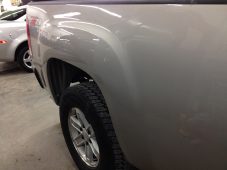 Rear bed side panel of a pickup truck after paintless dent repair, showing a smooth surface above the rear wheel.