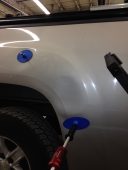Large dent visible on a vehicle quarter panel with glue tabs attached, before paintless dent repair.