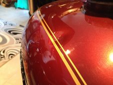 Harley-Davidson motorcycle fuel tank with visible dent before paintless dent repair at Collins Dent Werks in Fife Lake, Michigan