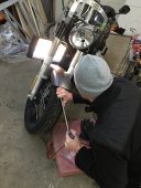 Technician performing paintless dent repair on a Harley-Davidson motorcycle at Collins Dent Werks in Fife Lake, Michigan
