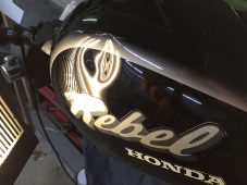Dent visible on Honda Rebel motorcycle fuel tank before paintless dent repair at Collins Dent Werks in Fife Lake, Michigan