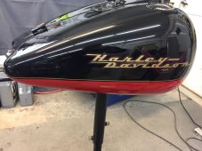 Harley-Davidson motorcycle fuel tank with visible dent before paintless dent repair at Collins Dent Werks in Fife Lake, Michigan