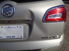 Dent visible on the rear hatch of a silver Buick Enclave next to the license plate area and right taillight.