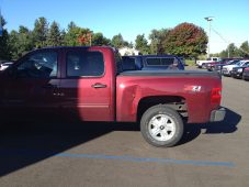 Dent visible on the bedside of a red pickup truck caused by a shopping cart before paintless dent repair.