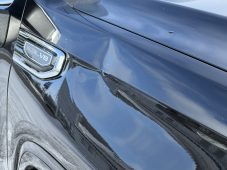 Close-up view of a dent on the front driver-side fender of a black GMC Sierra near the 5.3L V8 badge.